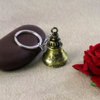 Close-up of a spiritual temple bell keychain crafted from durable metal.