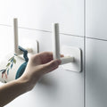 A set of two white hanging storage racks with adhesive hooks displayed in a modern kitchen, organizing spices and utensils.
