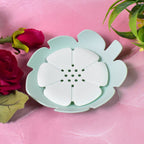 Set of two floral plastic soap dishes, one white and one pink, in a bathroom.