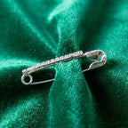 Silver safety pin brooch securing light fabric