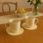 Lifestyle image showing two anti-slip silicone leaf coasters on a table