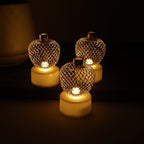 Decorative apple shaped LED tealight candle set lit on a table