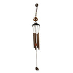 Side view of metal wind chime with Om symbol against green background
