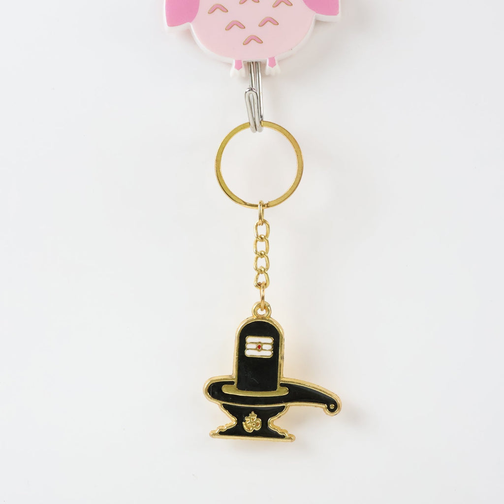 Golden Shivling keychain displayed on white surface showing metal craftsmanship