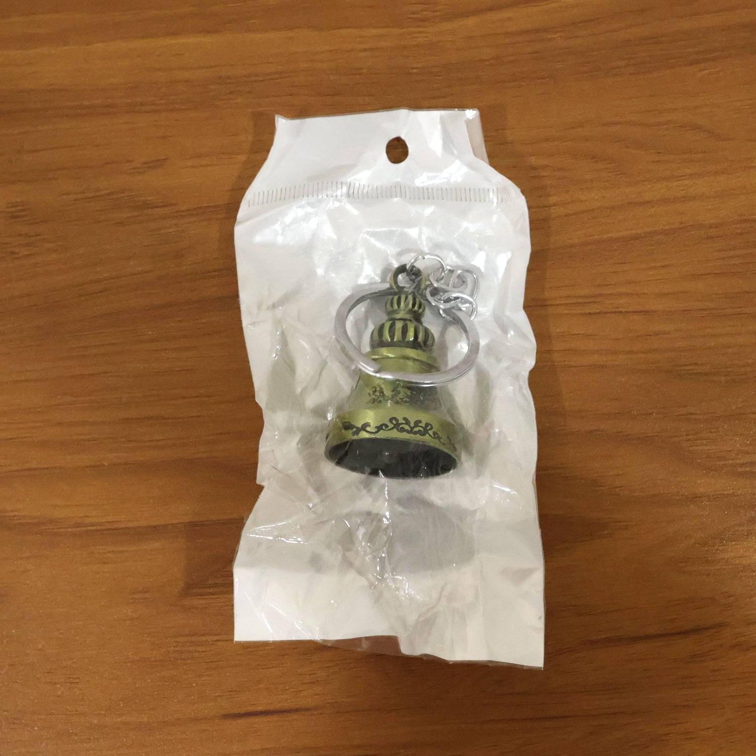 Metal temple bell keychain resting on a textured surface, showcasing its elegant form.