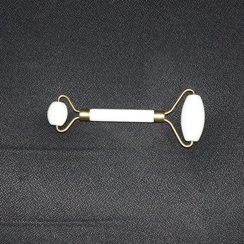 Dual-ended face massage roller displayed on a minimalist white background.