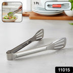 Steel kitchen serving tongs placed on a wooden table for food handling