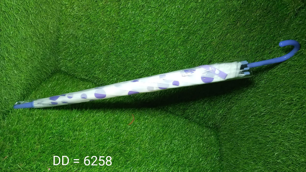 A closed white umbrella with purple geometric patterns and a blue handle lies on a green artificial grass surface.