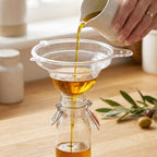 Funnel pouring oil into bottles in kitchen setting