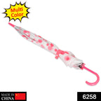 A closed white umbrella with pink polka dots and a curved pink handle lies diagonally on a white background.