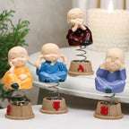 Baby monk figurines displayed on a car dashboard