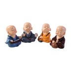 Set of four little monk statues on white background