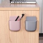 Wall mounted organizer holding a phone, remote, and pen.