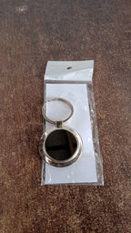 Close-up of round metal keychain with sleek black center and metal rim.