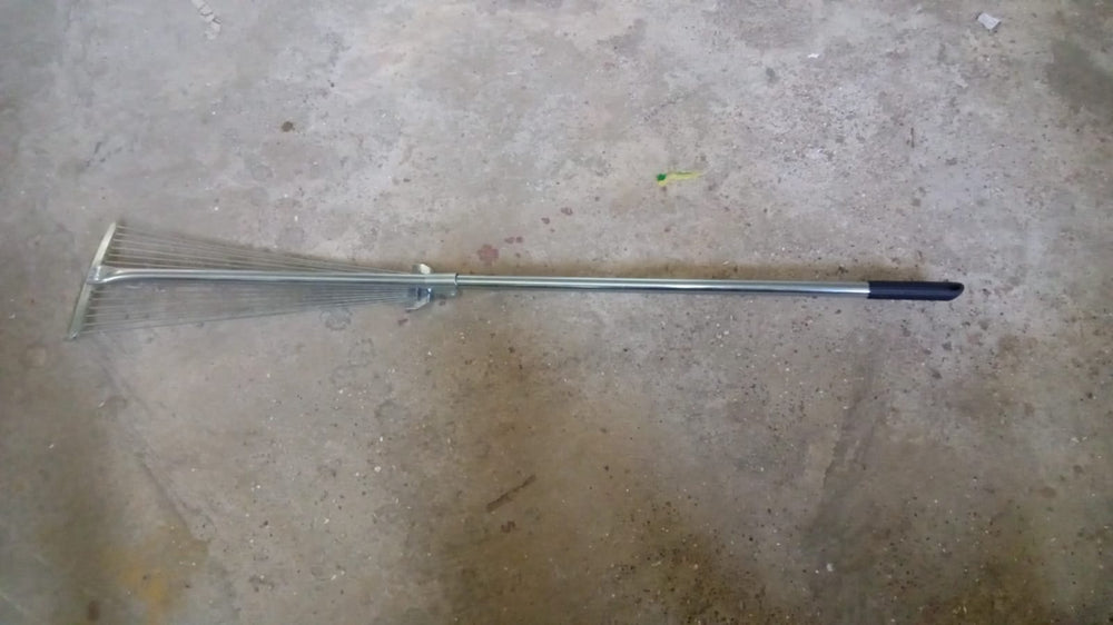 A gardener using the versatile garden rake to smooth soil in a neatly maintained yard.
