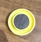 Yellow circular magnet placed next to pen for size reference