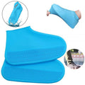 A pair of blue silicone rain boot covers with textured soles, one shown being stretched over a foot, and another in a puddle.