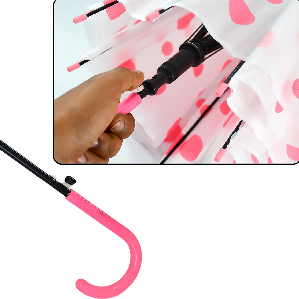 A close-up shows a hand operating the pink auto-open button on the handle of a pink polka dot umbrella.
