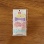 Young girl smiling wearing two cute cartoon hair clips showcasing real use.