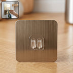 Self-adhesive wall hook with metallic finish and dual prongs for versatile hanging.