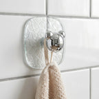 Close-up of clear plastic adhesive wall hook holding a kitchen towel securely.