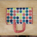 Person carrying large printed reusable shopping bag
